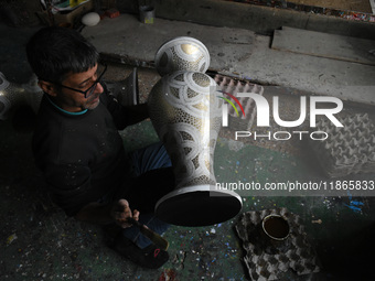 In Srinagar, Kashmir, India, on December 14, 2024, a Kashmiri artisan paints Christmas gift items at the workshop before sending them to the...