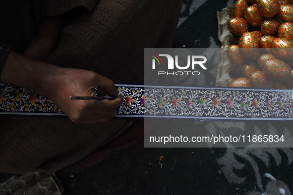 In Srinagar, Kashmir, India, on December 14, 2024, a Kashmiri artisan paints Christmas gift items at the workshop before sending them to the...