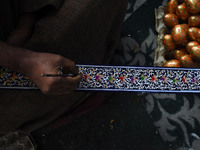 In Srinagar, Kashmir, India, on December 14, 2024, a Kashmiri artisan paints Christmas gift items at the workshop before sending them to the...