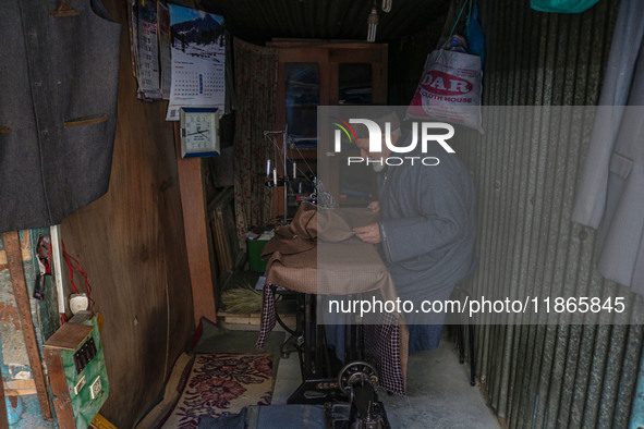 An elderly man sews clothes at a shop in Srinagar, Jammu and Kashmir, on December 14, 2024. 