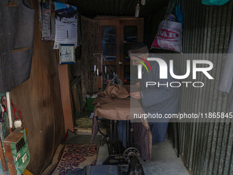 An elderly man sews clothes at a shop in Srinagar, Jammu and Kashmir, on December 14, 2024. (