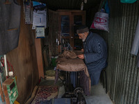 An elderly man sews clothes at a shop in Srinagar, Jammu and Kashmir, on December 14, 2024. (