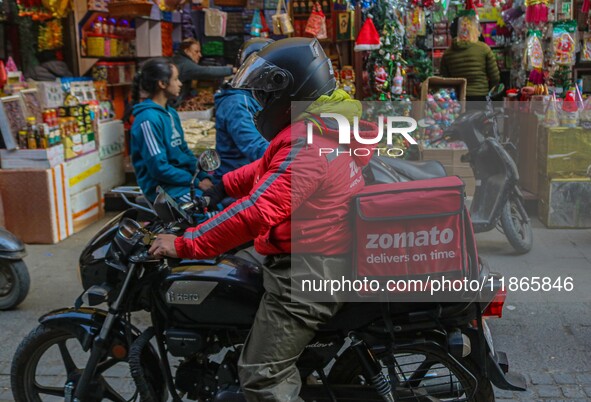 A deliveryman working for Zomato, an online food delivery application, rides a motorbike at a market in Srinagar, Jammu and Kashmir, on Dece...