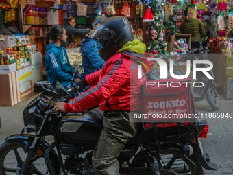 A deliveryman working for Zomato, an online food delivery application, rides a motorbike at a market in Srinagar, Jammu and Kashmir, on Dece...