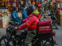 A deliveryman working for Zomato, an online food delivery application, rides a motorbike at a market in Srinagar, Jammu and Kashmir, on Dece...