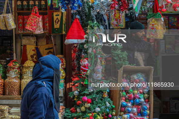 A woman walks past Santa Claus items in a shop at a market ahead of the Christmas celebrations in Srinagar, Jammu and Kashmir, on December 1...