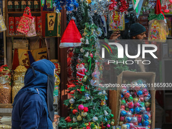 A woman walks past Santa Claus items in a shop at a market ahead of the Christmas celebrations in Srinagar, Jammu and Kashmir, on December 1...