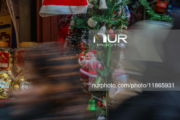 People walk past a Santa Claus decorative article displayed at a market ahead of the Christmas celebrations in Srinagar, Jammu and Kashmir,...