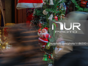 People walk past a Santa Claus decorative article displayed at a market ahead of the Christmas celebrations in Srinagar, Jammu and Kashmir,...