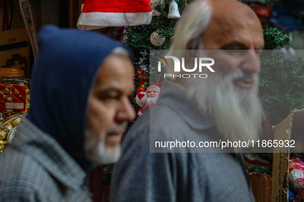 People walk past a Santa Claus decorative article displayed at a market ahead of the Christmas celebrations in Srinagar, Jammu and Kashmir,...