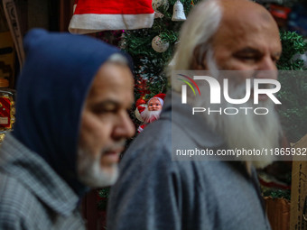 People walk past a Santa Claus decorative article displayed at a market ahead of the Christmas celebrations in Srinagar, Jammu and Kashmir,...