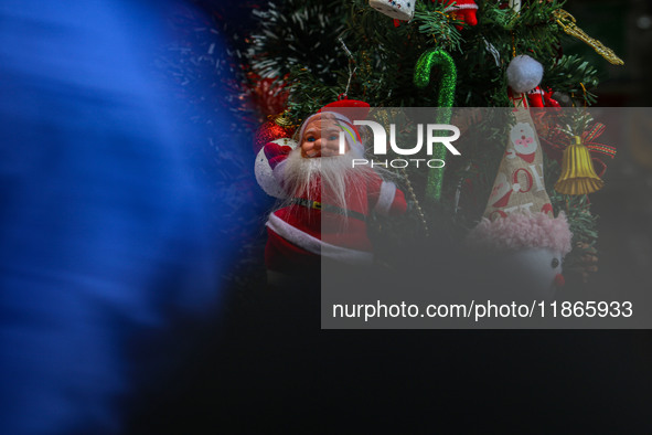 People walk past a Santa Claus decorative article displayed at a market ahead of the Christmas celebrations in Srinagar, Jammu and Kashmir,...