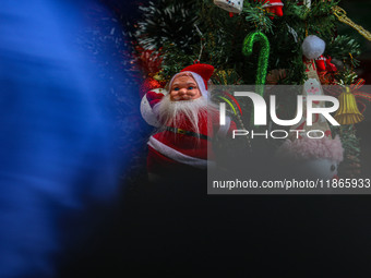 People walk past a Santa Claus decorative article displayed at a market ahead of the Christmas celebrations in Srinagar, Jammu and Kashmir,...