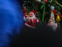 People walk past a Santa Claus decorative article displayed at a market ahead of the Christmas celebrations in Srinagar, Jammu and Kashmir,...