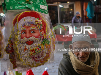 An elderly man looks on as Santa Claus items are seen in a shop at a market ahead of the Christmas celebrations in Srinagar, Jammu and Kashm...