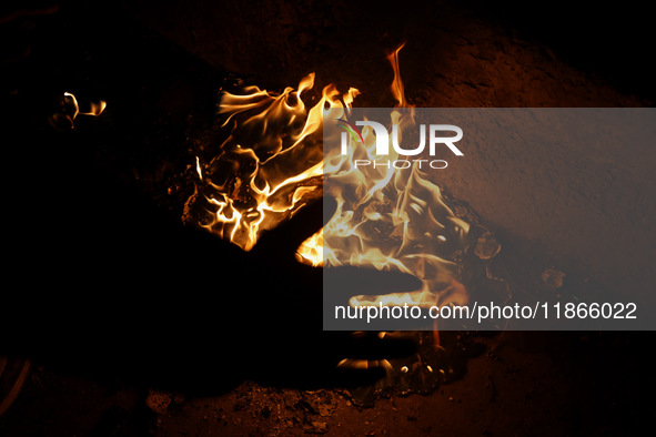 A man warms his hands by a fire during a cold winter evening in Sopore, Jammu and Kashmir, India, on December 14, 2024. 