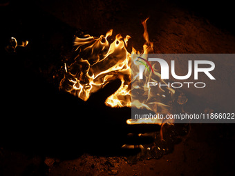 A man warms his hands by a fire during a cold winter evening in Sopore, Jammu and Kashmir, India, on December 14, 2024. (