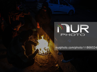 Kashmiri boys warm their hands on a bonfire in Sopore, Jammu and Kashmir, India, on December 14, 2024. (