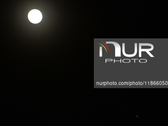 The planet Venus appears as the Moon is visible in the night sky in Siliguri, India, on December 14, 2024. (