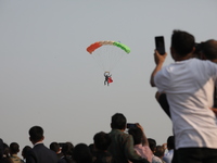 People watch as an Indian army paratrooper jumps from a plane carrying a flag during the full dress rehearsal ahead of ''Vijay Diwas,'' a ce...