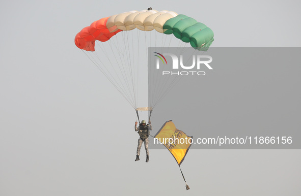 An Indian army paratrooper jumps from a plane carrying a flag during the full dress rehearsal ahead of ''Vijay Diwas,'' a ceremony to celebr...