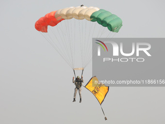 An Indian army paratrooper jumps from a plane carrying a flag during the full dress rehearsal ahead of ''Vijay Diwas,'' a ceremony to celebr...