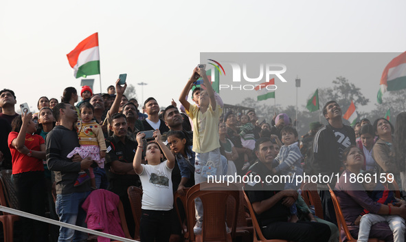 People watch Indian Army personnel with helicopters perform a drill during the full dress rehearsal ahead of ''Vijay Diwas'', a ceremony to...