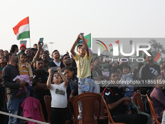 People watch Indian Army personnel with helicopters perform a drill during the full dress rehearsal ahead of ''Vijay Diwas'', a ceremony to...