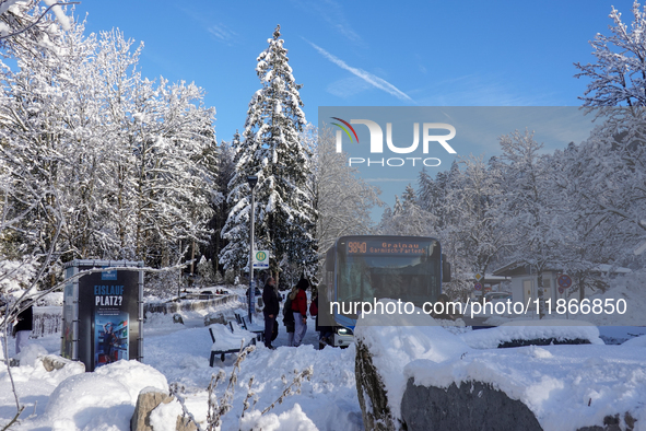 Passengers wait for the bus to Grainau amidst the snowy landscape at Lake Eibsee in Bavaria, Germany, on December 13, 2024. A group of peopl...