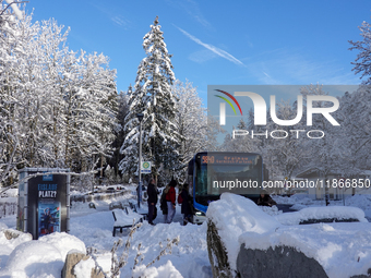 Passengers wait for the bus to Grainau amidst the snowy landscape at Lake Eibsee in Bavaria, Germany, on December 13, 2024. A group of peopl...