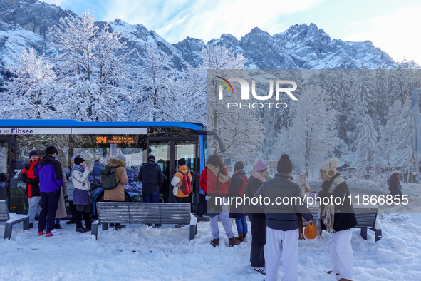 Passengers wait for the bus to Grainau amidst the snowy landscape at Lake Eibsee in Bavaria, Germany, on December 13, 2024. A group of peopl...