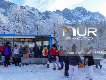 Passengers wait for the bus to Grainau amidst the snowy landscape at Lake Eibsee in Bavaria, Germany, on December 13, 2024. A group of peopl...