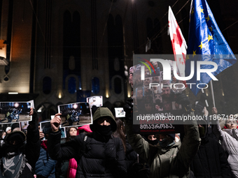 Anti-government demonstrators gather outside the Georgian parliament after the parliament members elect a new president in Tbilisi, Georgia,...