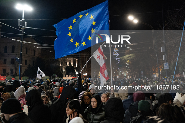 Anti-government demonstrators gather outside the Georgian parliament after the parliament members elect a new president in Tbilisi, Georgia,...