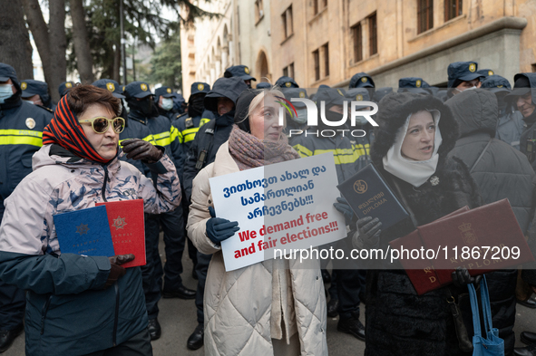 Anti-government demonstrators gather outside the Georgian parliament after the parliament members elect a new president in Tbilisi, Georgia,...