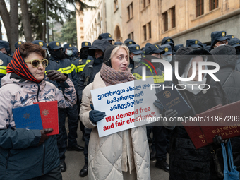 Anti-government demonstrators gather outside the Georgian parliament after the parliament members elect a new president in Tbilisi, Georgia,...