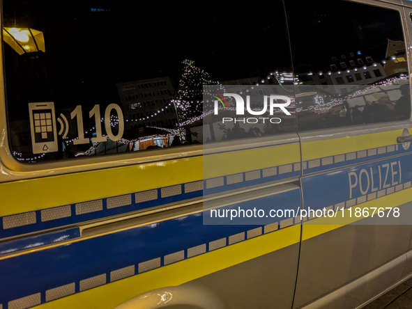 A police vehicle parks amidst the festive glow at Augsburg's Christmas market, ensuring security for holiday visitors in Augsburg, Germany,...