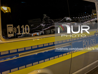 A police vehicle parks amidst the festive glow at Augsburg's Christmas market, ensuring security for holiday visitors in Augsburg, Germany,...