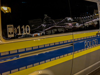 A police vehicle parks amidst the festive glow at Augsburg's Christmas market, ensuring security for holiday visitors in Augsburg, Germany,...