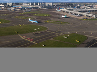 Aerial panoramic view of Amsterdam Airport Schiphol AMS EHAM from a departing airplane window. Aircraft, airport terminal, cargo terminal, r...