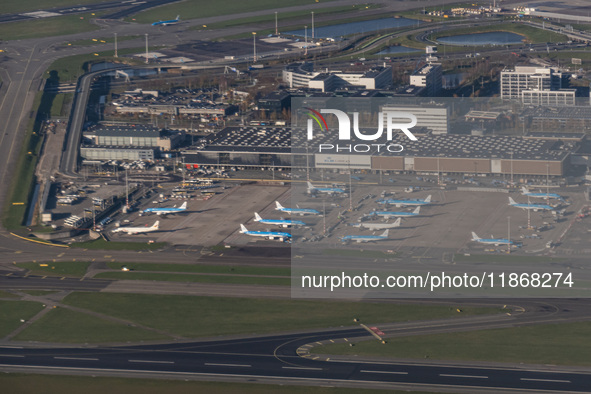 Aerial panoramic view of Amsterdam Airport Schiphol AMS EHAM from a departing airplane window. Aircraft, airport terminal, cargo terminal, r...