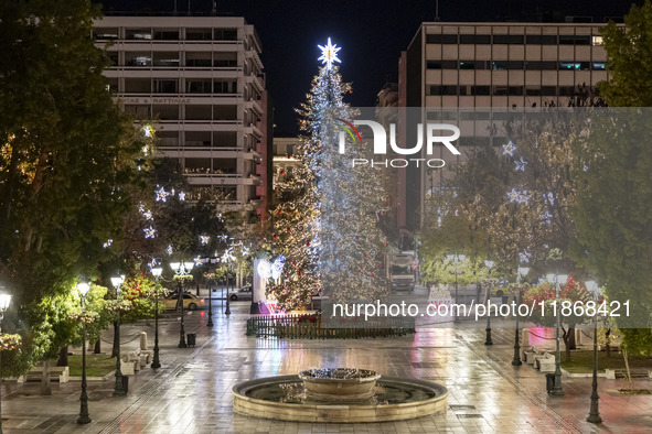 Festive night view of the iconic Syntagma Square adorned with dazzling Christmas decorations, featuring a towering Christmas tree illuminate...