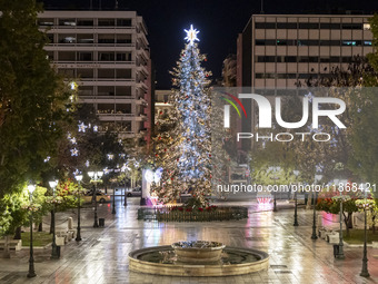 Festive night view of the iconic Syntagma Square adorned with dazzling Christmas decorations, featuring a towering Christmas tree illuminate...