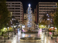 Festive night view of the iconic Syntagma Square adorned with dazzling Christmas decorations, featuring a towering Christmas tree illuminate...