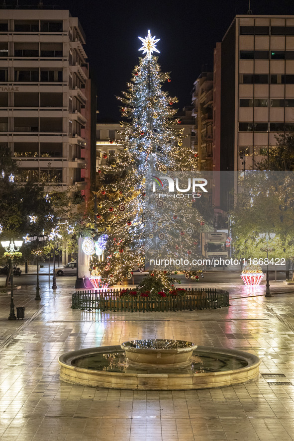 Festive night view of the iconic Syntagma Square adorned with dazzling Christmas decorations, featuring a towering Christmas tree illuminate...