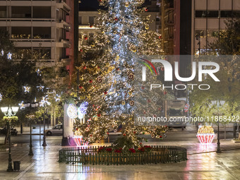 Festive night view of the iconic Syntagma Square adorned with dazzling Christmas decorations, featuring a towering Christmas tree illuminate...