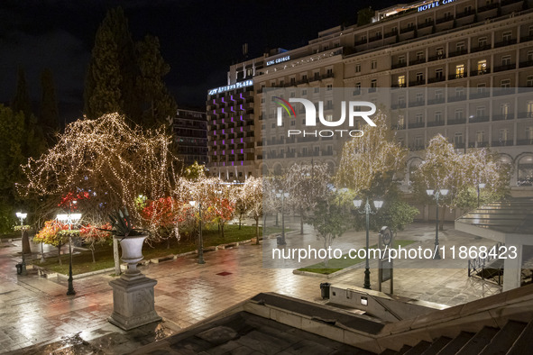 Festive night view of the iconic Syntagma Square adorned with dazzling Christmas decorations, featuring a towering Christmas tree illuminate...