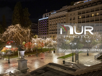 Festive night view of the iconic Syntagma Square adorned with dazzling Christmas decorations, featuring a towering Christmas tree illuminate...