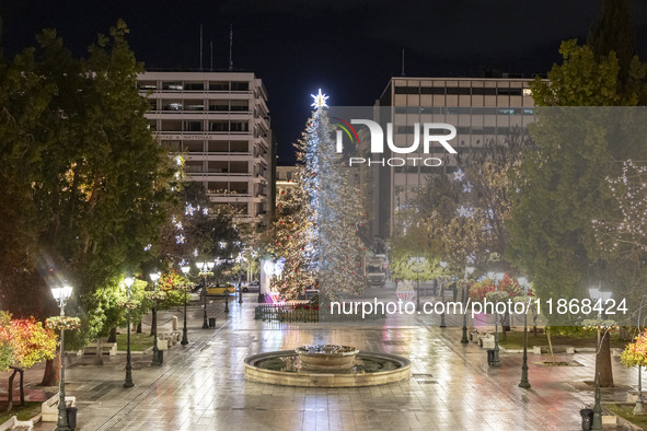 Festive night view of the iconic Syntagma Square adorned with dazzling Christmas decorations, featuring a towering Christmas tree illuminate...