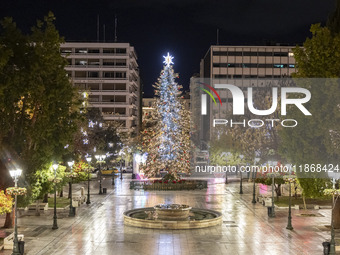 Festive night view of the iconic Syntagma Square adorned with dazzling Christmas decorations, featuring a towering Christmas tree illuminate...